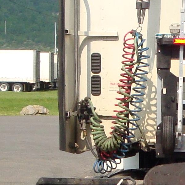 Red and blue coiled air brake lines hanging at the back of a tractor